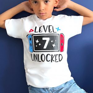 Boy wearing personalised Nintendo Switch birthday t-shirt with 'Level 7 Unlocked' design, perfect gaming gift for kids aged 2–13.