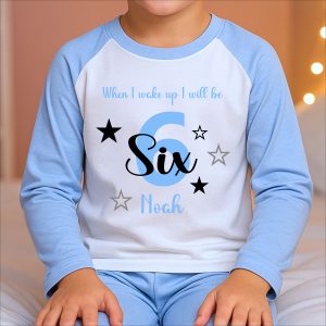 Boy wearing personalised blue birthday eve pyjamas with age six and name Noah